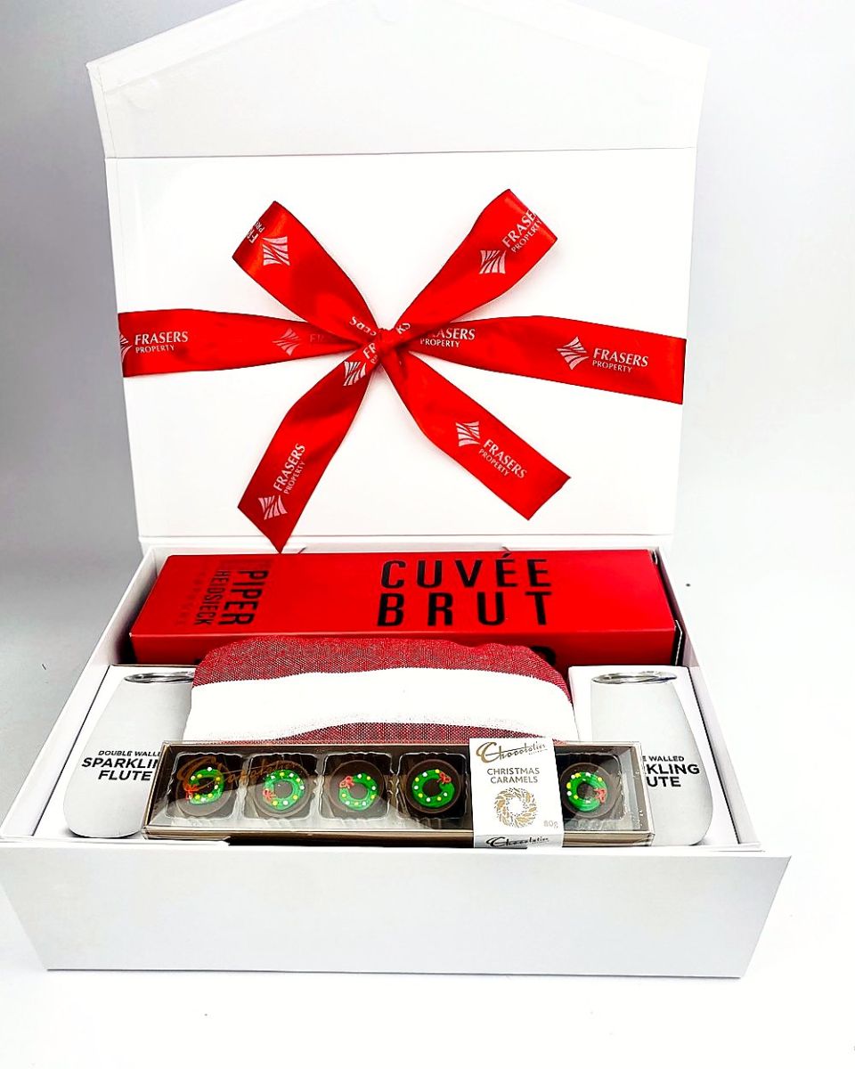 White gift box with a client-branded red ribbon, holding Champagne, flutes and Christmas caramels